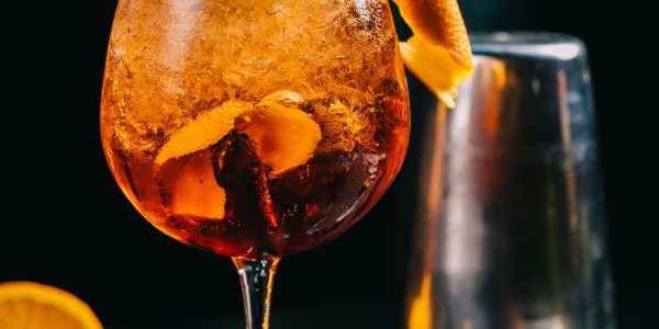 cocktail-arancione-all-interno-di-vetro-con-cubetti-di-ghiaccio-tritato-e-tubi_114579-2940